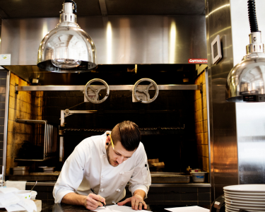 Kitchen staff member writing on menu