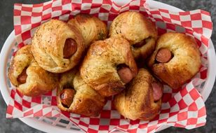 Plastic basket lined with paper filled with multiple Hot Dog Cruffins.