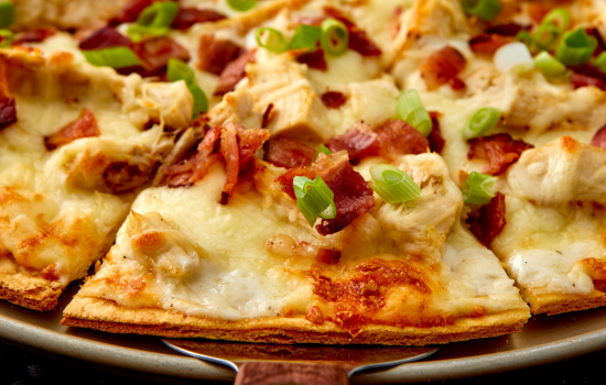 A closeup of a ready-to-serve Cheese Bacon Ranch Pizza slice made from thin BONICI® parbaked crust.