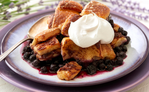 Cinnamon roll served cobbler style over blueberries and topped with cream