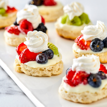 Biscuit tartlets topped with a variety of summer berries and whipped cream